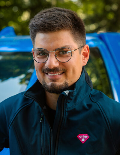 Portrait de Jules, devant son pick-up d'intervention rose et bleu. Déboucheur franchisé de la Compagnie des Déboucheurs sur le département de la Mayenne